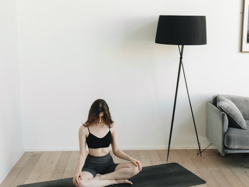 Man in a dynamic stretching pose in a spacious room.